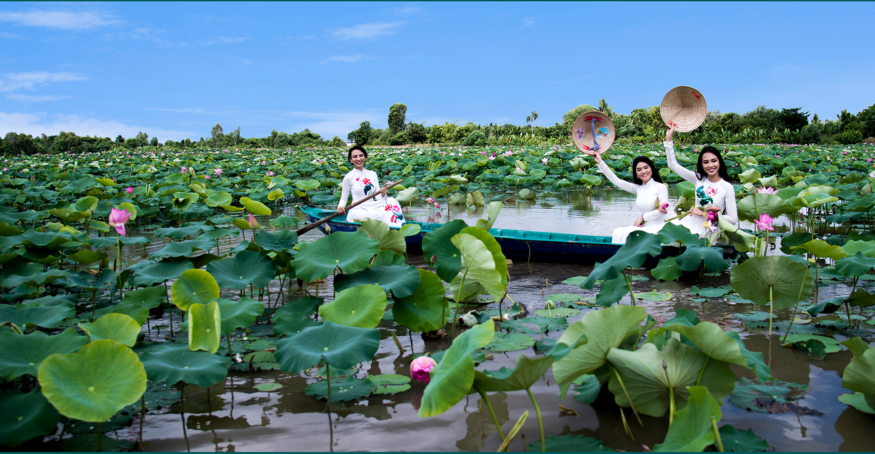 Three women in traditional dress among lotus flowers